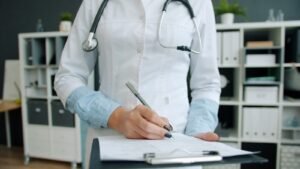Doctor writing on a clipboard in an office while reviewing billing documentation