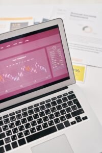 Laptop showing financial graphs alongside printed reports